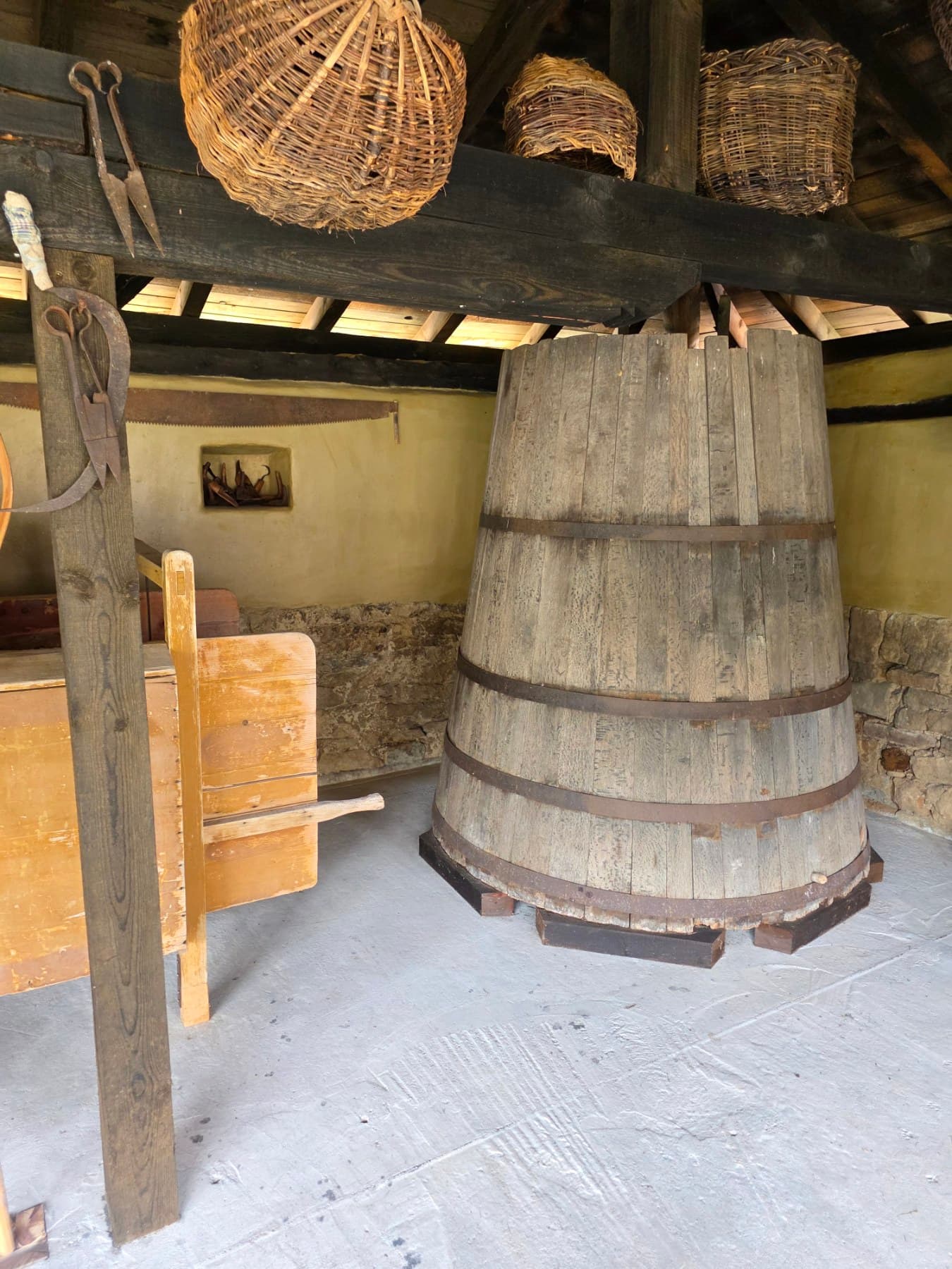 A large wooden vessel and woven baskets in the courtyard shelter