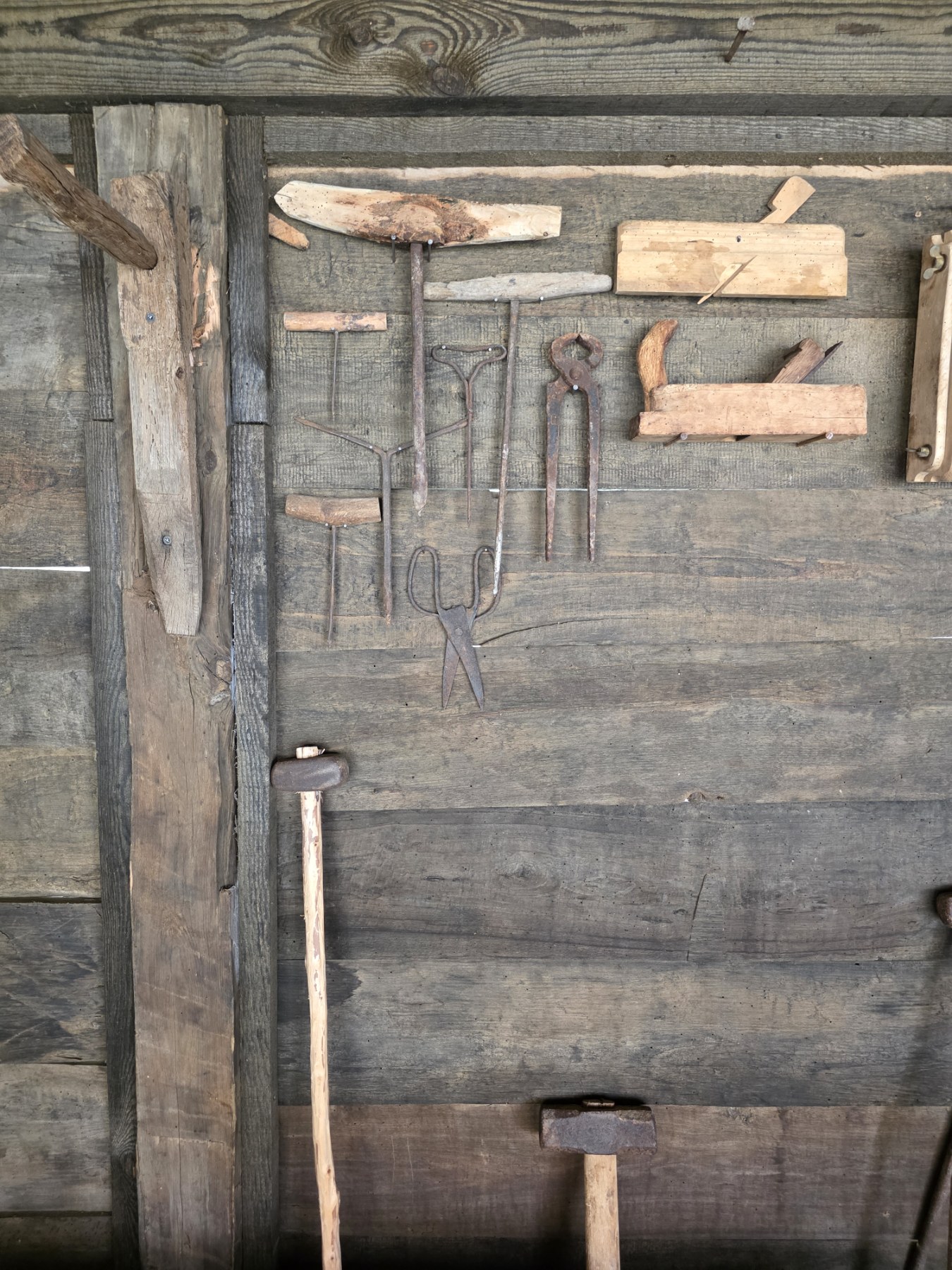 Old hand tools displayed on a timber wall