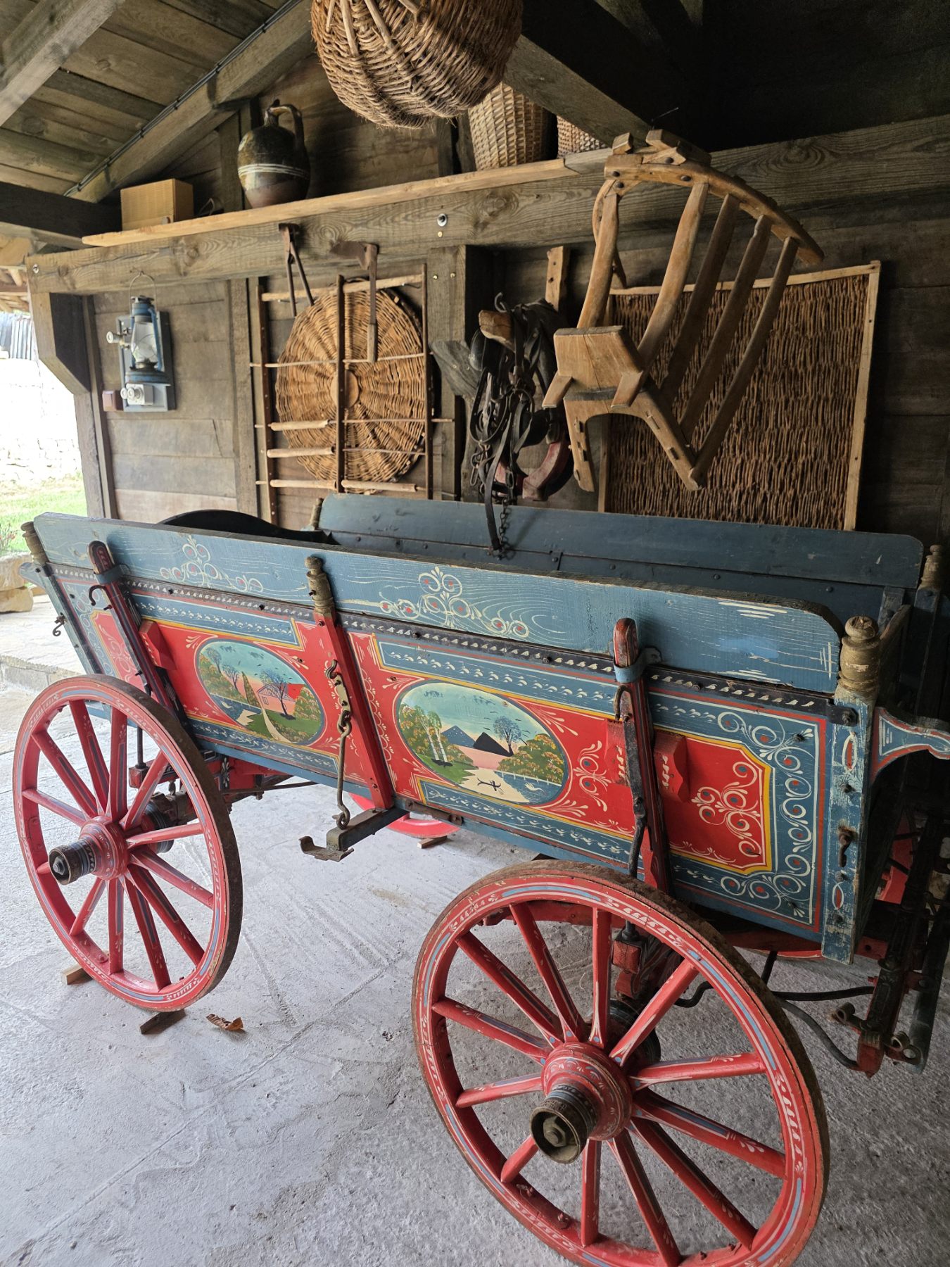 A wooden cart with red wheels and painted side panels