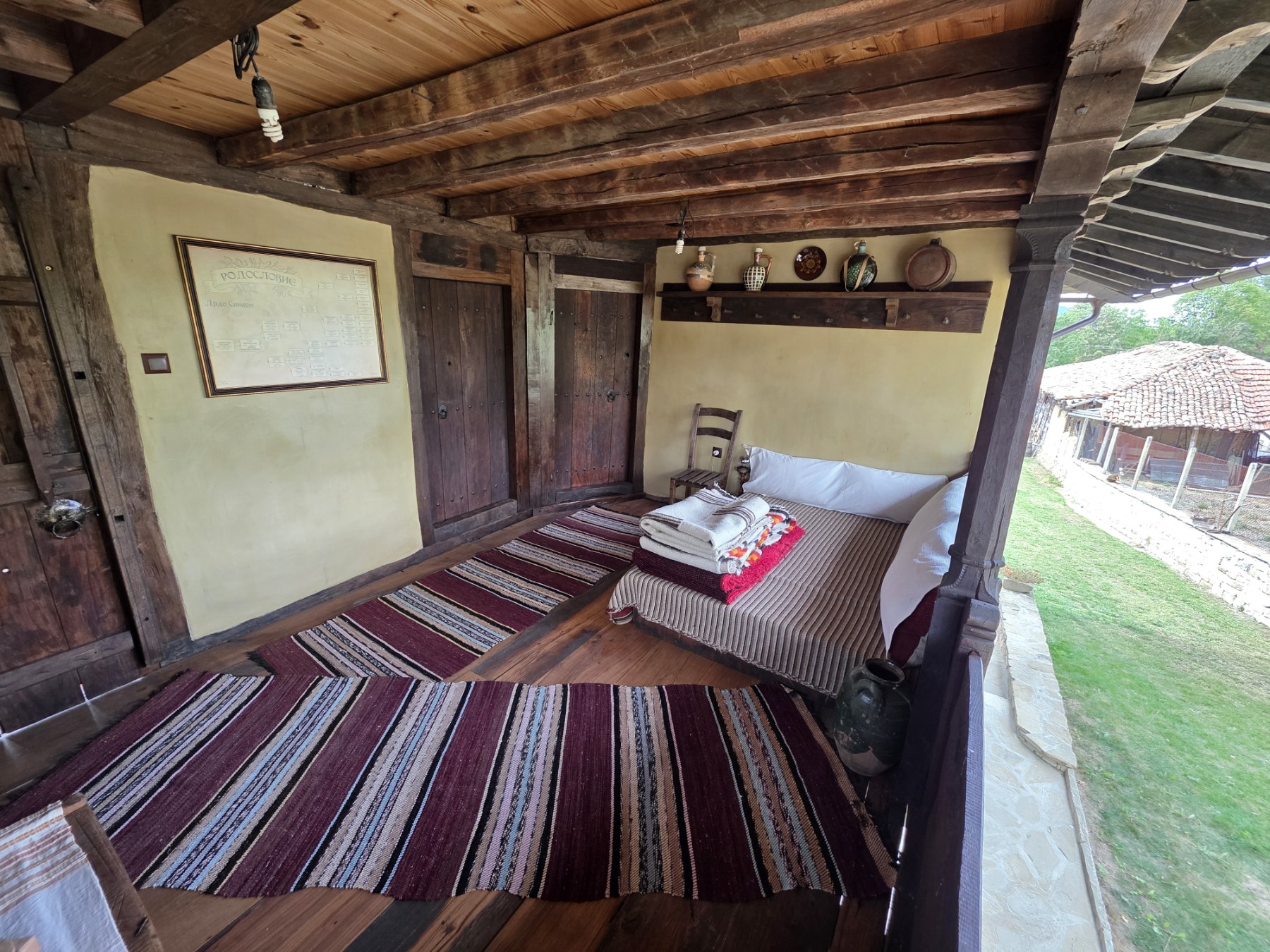 A wooden veranda with woven rugs and folded textiles